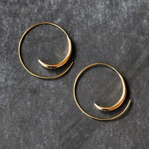 May include: A pair of gold hoop earrings with a unique spiral design. The earrings are made of thin metal and have a simple, elegant look.
