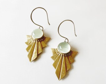 May include: A pair of gold earrings with a geometric design and a light green stone in the center of each earring.