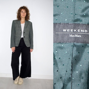 Op de afbeelding: Een groene blazer met een geruit patroon en een label met de tekst "Weekend MaxMara".