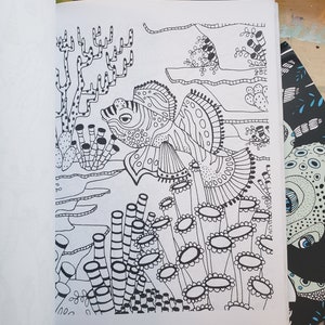 A coloring book page with mandarin fish swimming amongst sea vegetation