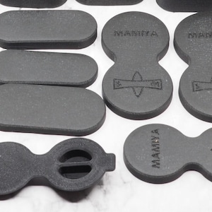 May include: A set of black foam camera lens caps with the text "Mamiya" printed on them. The caps are designed for different lens sizes and have a variety of shapes.
