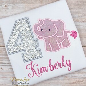May include: A white t-shirt with a silver glitter number 4, a pink elephant, and the name Kimberly embroidered in pink.