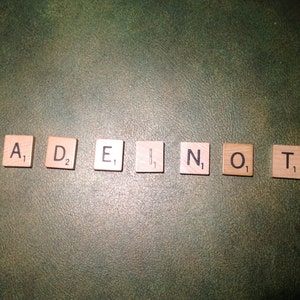 May include: Wooden letter tiles spelling out the word "ADENO" on a green background.