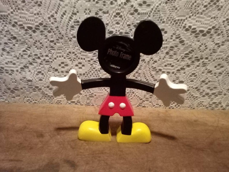 May include: Black plastic Mickey Mouse photo frame with a red and white polka dot shirt, white gloves, and yellow shoes. The frame says "Disney Photo Frame" on the front.
