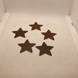 May include: Five brown metal star-shaped coasters. The coasters are rustic and have a textured surface.