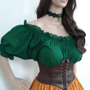 May include: A green off-the-shoulder peasant top with brown leather corset and a long orange skirt. The model is wearing a flower crown.
