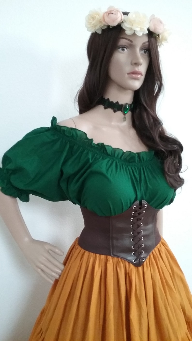 May include: A green off-the-shoulder peasant top with brown leather corset and a long orange skirt. The model is wearing a flower crown.