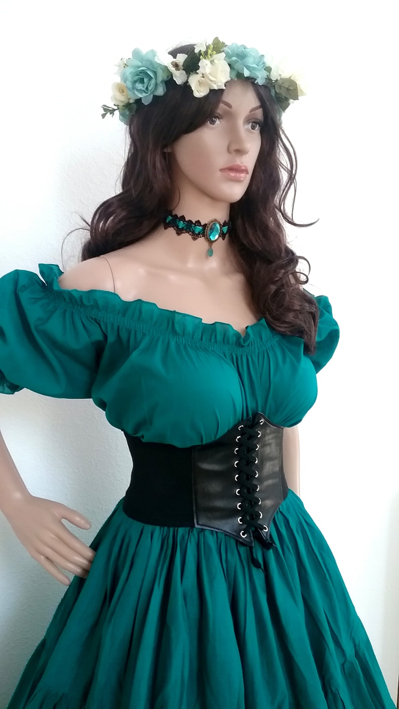 May include: A teal off-the-shoulder peasant top with a black leather corset and a teal skirt. The model is wearing a flower crown with white and blue flowers.