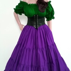 May include: A purple, tiered skirt with a green, off-the-shoulder blouse and a black corset. The model is wearing a flower crown with purple and white flowers.