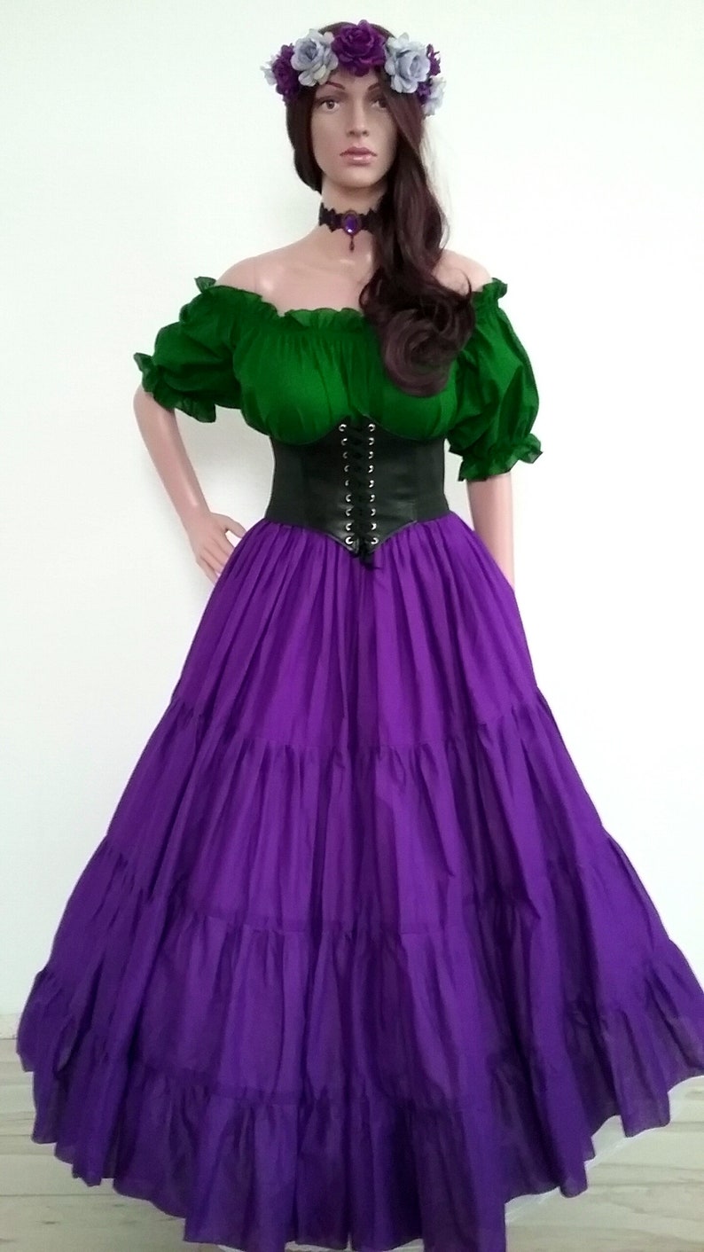 May include: A purple, tiered skirt with a green, off-the-shoulder blouse and a black corset. The model is wearing a flower crown with purple and white flowers.