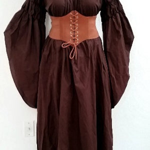K&ouml;nnte beinhalten: Ein braunes Kleid im mittelalterlichen Stil mit langen, flie&szlig;enden &Auml;rmeln und einem eng anliegenden braunen Korsett. Das Kleid hat einen Rundhalsausschnitt und einen weiten Rock. Das Korsett ist vorne mit einer braunen Kordel geschn&uuml;rt.