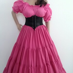 May include: A pink, tiered, full-length skirt with a black corset and a flower crown. The skirt has a ruffled neckline and short sleeves.