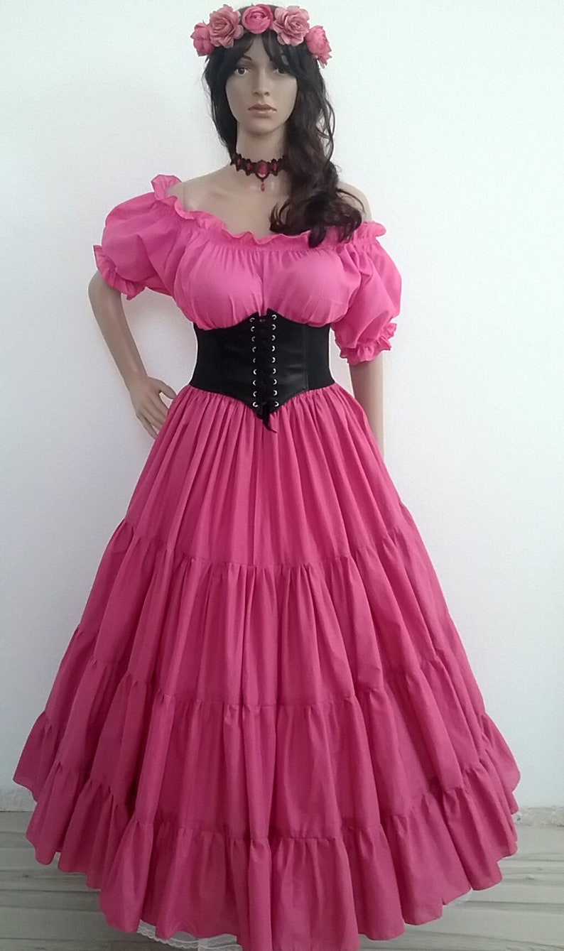 May include: A pink, tiered, full-length skirt with a black corset and a flower crown. The skirt has a ruffled neckline and short sleeves.