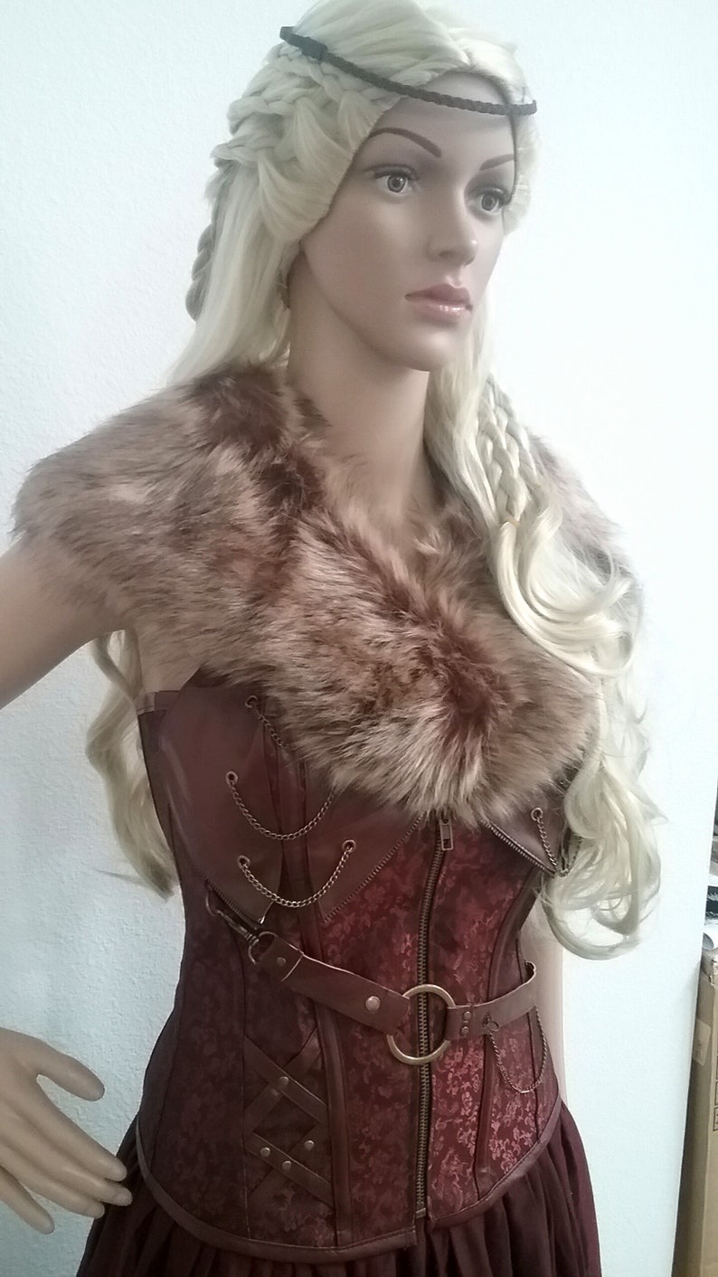 Puede incluir: Un collar de piel sint&eacute;tica marr&oacute;n para mujer con un cors&eacute; rojo y marr&oacute;n con cremallera y detalles met&aacute;licos decorativos. El cors&eacute; tiene un cintur&oacute;n de cuero marr&oacute;n con un gran anillo met&aacute;lico.