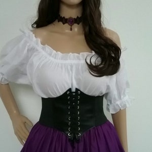 May include: A woman wearing a white peasant top with a black corset and a purple skirt. She is wearing a flower crown with purple and white flowers.