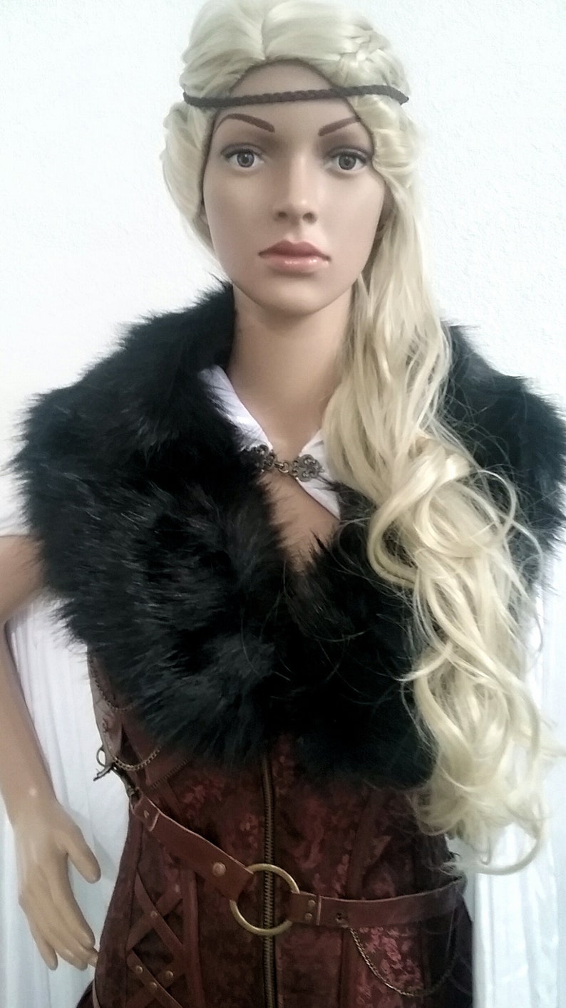 Puede incluir: Una mujer con un cors&eacute; de cuero marr&oacute;n con un cuello de piel negra y un cintur&oacute;n de cuero marr&oacute;n con una hebilla de metal. Lleva una camisa blanca debajo del cors&eacute; y tiene el pelo rubio con una diadema marr&oacute;n.