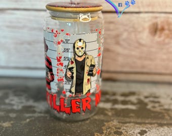 May include: A clear glass tumbler with a wooden lid and a clear straw. The tumbler features a mugshot design with a horror movie theme, including the text "KILLER" in red. The design includes a height chart and images of horror characters.
