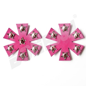 Puede incluir: Dos parches de estrella rosa con tachuelas plateadas. Cada parche tiene ocho puntas y una estrella plateada en el centro.