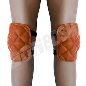 May include: A pair of orange quilted knee pads with black elastic straps. The knee pads are designed to protect knees from injury while kneeling.