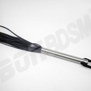 May include: A black leather whip with a silver handle and a black leather loop. The whip has a long, thin handle and a thick, braided head.