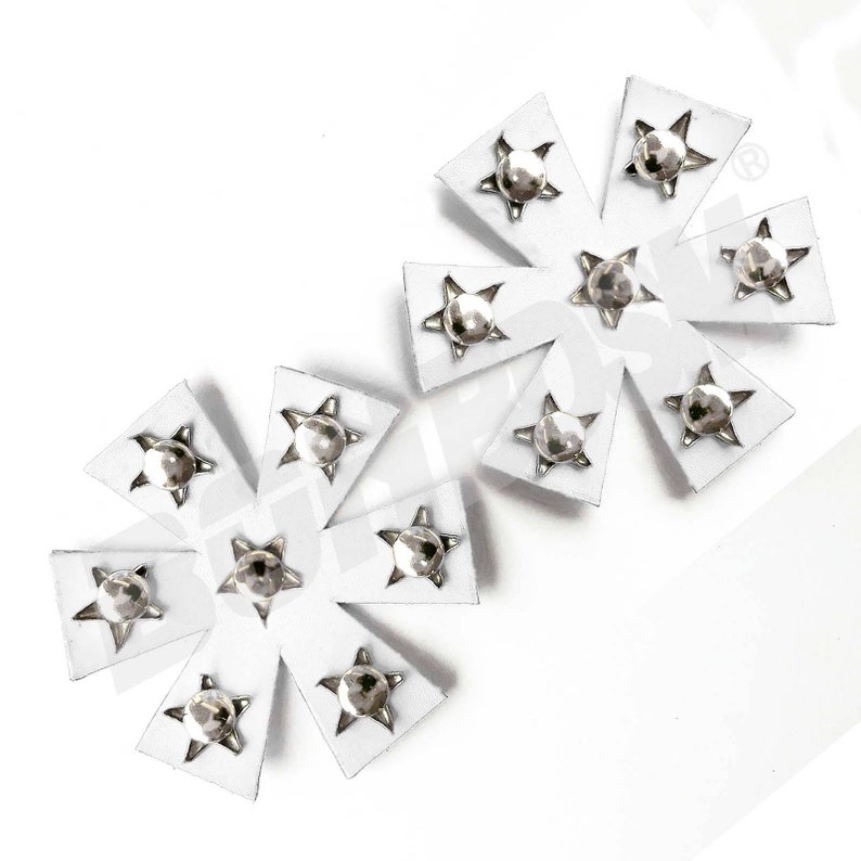 Puede incluir: Dos parches de cuero blanco en forma de estrella con tachuelas plateadas en el centro de cada punta.