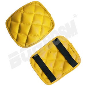 May include: Two yellow quilted leather motorcycle seat pads. One pad has a black strap across the top.