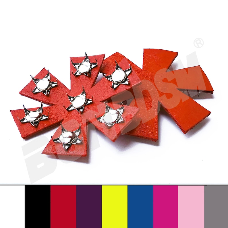 Puede incluir: Dos parches de cuero rojo en forma de estrella con tachuelas plateadas. Cada parche tiene seis puntas y una tachuela plateada en el centro de cada punta.