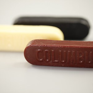 May include: Three sticks of shoe polish, one white, one black, and one red with the word "COLUMBUS" embossed on it.