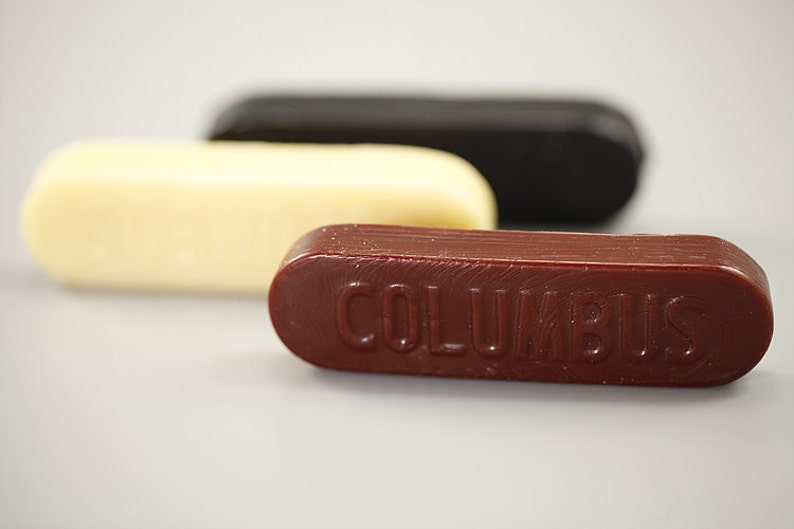 May include: Three sticks of shoe polish, one white, one black, and one red with the word "COLUMBUS" embossed on it.
