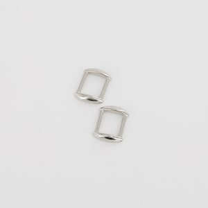 May include: Two silver metal D-rings, each with a rounded rectangular shape.
