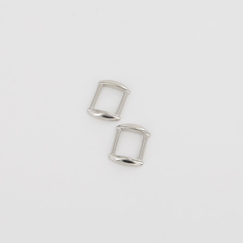 May include: Two silver metal D-rings, each with a rounded rectangular shape.