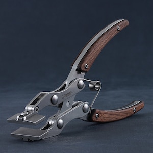 May include: A silver metal tool with wooden handles. The tool has a spring and a lever. The tool is labelled "Nattools".