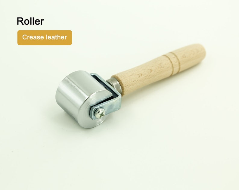 May include: A silver roller with a wooden handle. The roller is used to crease leather.