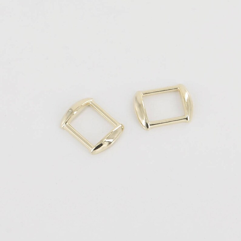May include: Two gold-toned metal slider buckles, one rectangular and one square.