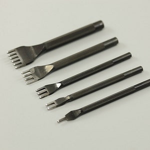 Könnte beinhalten: Satz von fünf Leder-Steppwerkzeugen mit verschiedenen Stempelgrößen. Die Werkzeuge sind aus Metall und haben eine schwarze Oberfläche.