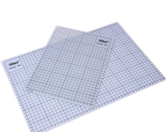 Könnte beinhalten: Zwei weiße selbstheilende Schneidematten mit einem Gittermuster. Die Matten sind mit "9Sea® Cutting Mat" beschriftet.
