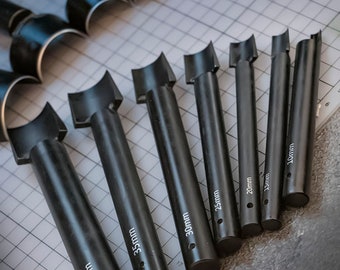 May include: Set of eight black leather punch tools with different sizes, ranging from 15mm to 40mm. Each tool has a curved edge and a handle.