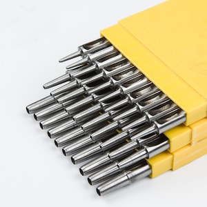 May include: A set of 18 metal hole punches in a yellow plastic case. The punches are arranged in order of size, with the smallest punch at the top and the largest punch at the bottom.