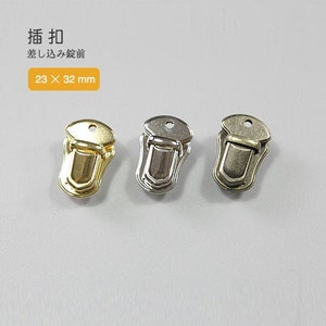 Pode incluir: Três fechos metálicos, um dourado e dois prateados, com um design decorativo. Os fechos medem 23 x 32 mm.