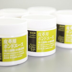 K&ouml;nnte beinhalten: Vier wei&szlig;e Gl&auml;ser mit Lederkleber mit gr&uuml;nen und schwarzen Etiketten. Das Etikett lautet "Leather Adhesive" und "Seiwa Leather Craft". Der Text auf dem Etikett ist in Japanisch und Englisch.