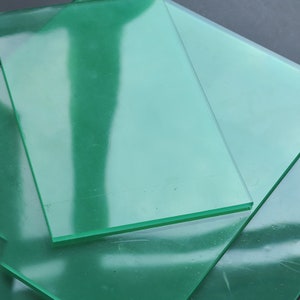 Peut inclure: Pile de trois feuilles d'acrylique transparentes de couleur verte. Les feuilles sont translucides et ont un l&eacute;ger &eacute;clat.