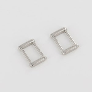 Peut inclure: Deux boucles coulissantes rectangulaires en métal argenté. Les boucles mesurent environ 2,5 cm de long et 1,25 cm de large.