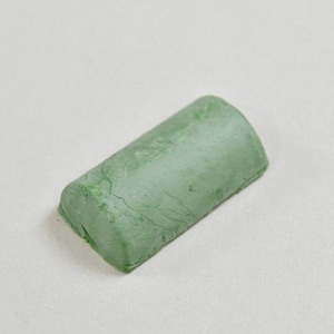 May include: A green polishing compound bar for metalworking.