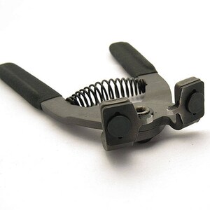 May include: A black and silver metal tool with a spring and two rubber pads. The tool is used for setting eyelets.