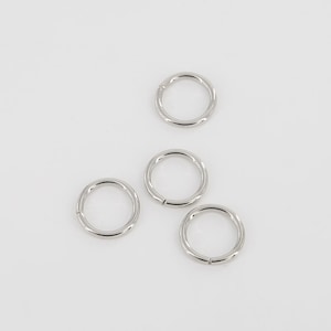 Puede incluir: Cuatro anillos de salto plateados, cada uno con una forma circular y un acabado liso y pulido.