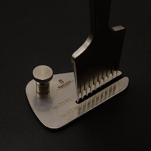 May include: A silver metal tool with a handle and a row of prongs. The tool is labeled "No.7(3.85)" and "No.2(3.38)".