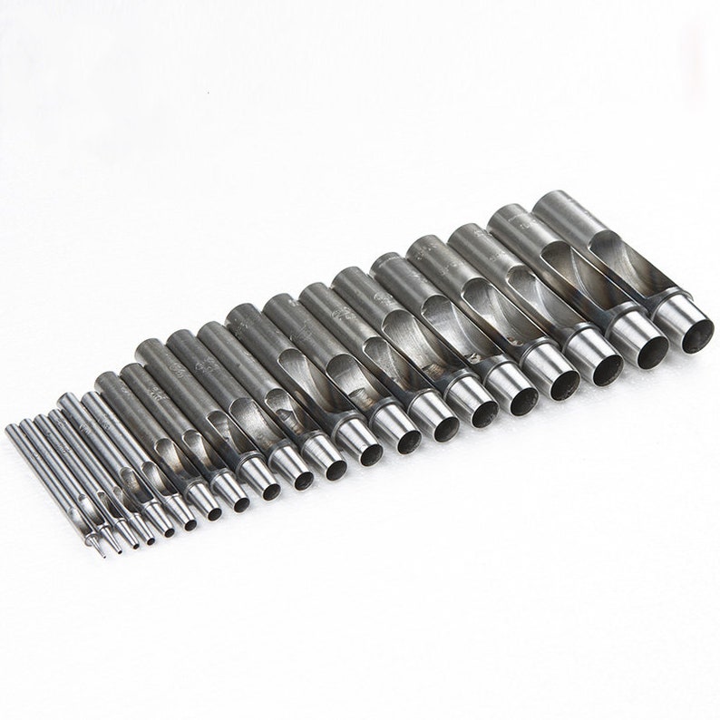 May include: A set of 18 silver metal hole punch tools of varying sizes. The tools are arranged in a row from largest to smallest.