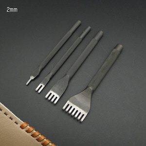 Può includere: Quattro strumenti di cucito in pelle neri con punte di diverse dimensioni. Gli strumenti sono disposti dal più grande al più piccolo. Gli strumenti sono su una superficie grigio scuro. 2mm è scritto nell'angolo in alto a sinistra dell'immagine.