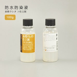 Peut inclure: Deux flacons en plastique transparent de finition polyuréthane à base d'eau, chacun contenant 100 grammes de produit. Les flacons ont des bouchons noirs et des étiquettes avec du texte japonais.