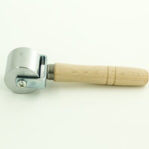 May include: A silver roller with a wooden handle. The roller is used for smoothing out surfaces.
